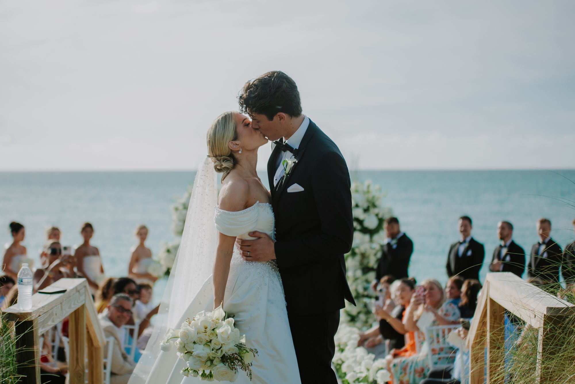 sarah and jackson kissing at beaches turks and caicos with friends and family in the background